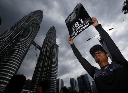 FILE PHOTO: A man holds up a poster during a 1MDB protest organized by Pro-democracy group Bersih, calling for Malaysian Prime Minister Najib Abdul Razak to resign, in Kuala Lumpur, Malaysia November 19, 2016. REUTERS/Edgar Su/File Photo