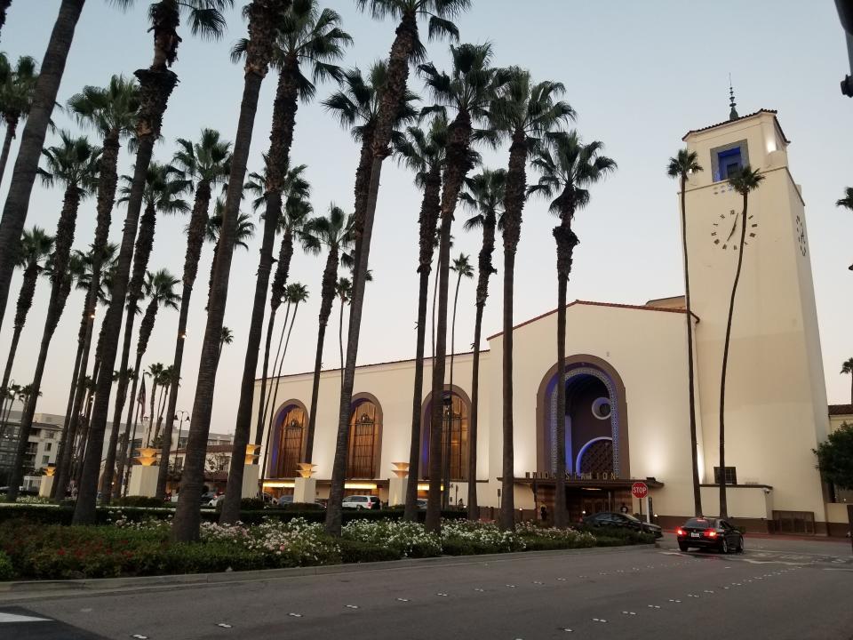 A train station with multiple palm trees in the foreground.