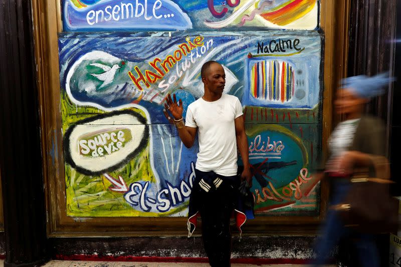 Belgian artist Atumesa poses in front of his fresco in the Matonge district of Brussels