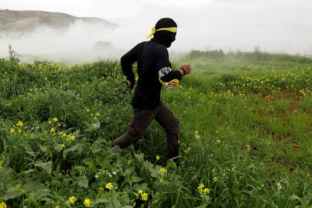 A Palestinian demonstrator runs from tear gas fired by Israeli troops during a protest marking the Land Day in al-Mughayer village, in the Israeli-occupied West Bank March 29, 2019. REUTERS/Mohamad Torokman