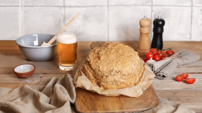 Loaf of rustic bread on a kitchen counter with a glass of beer