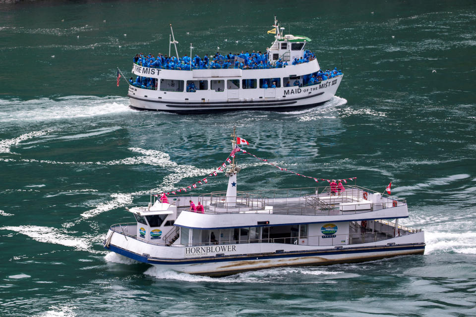 American tourist boat Maid Of The Mist, limited to 50 per cent occupancy glides past a Canadian vessel limited under Ontario's rules to just six passengers. Source: Reuters