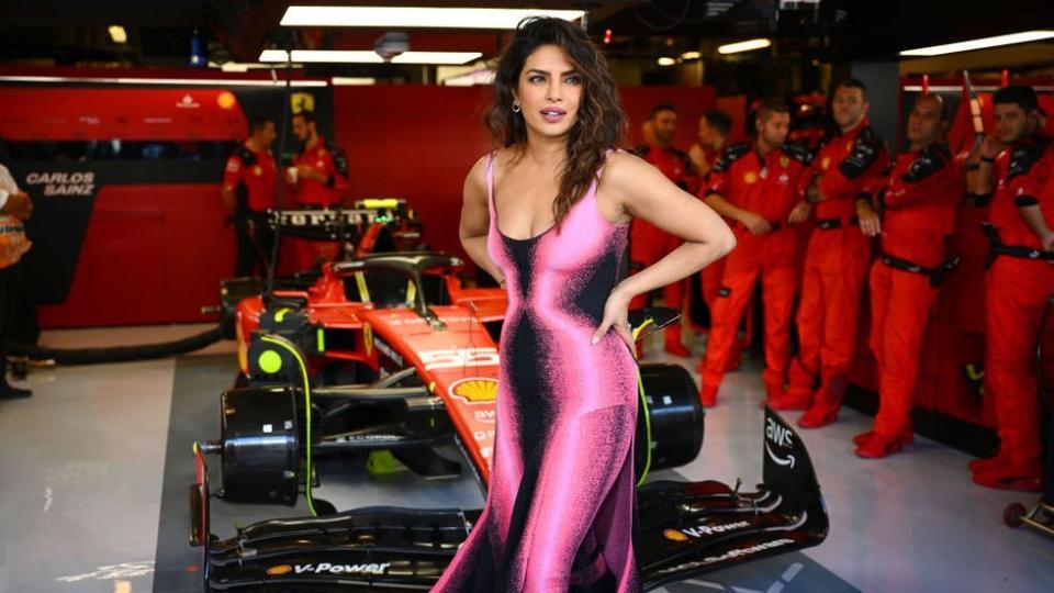 a woman in a dress standing next to a race car