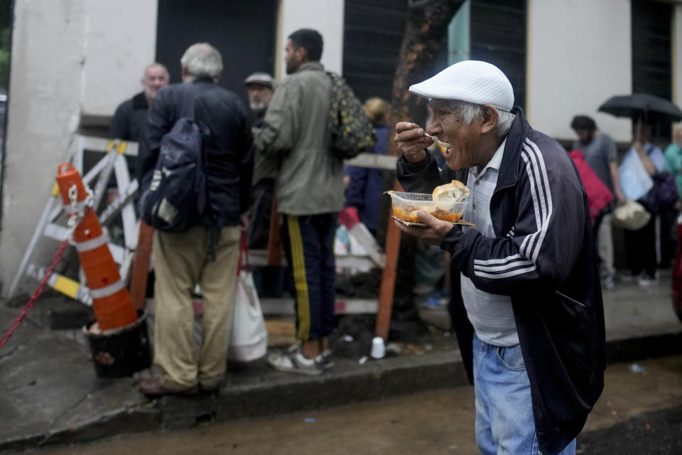 Mario Cardozo come una comida caliente gratis afuera de un comedor comunitario dirigido por el Movimiento de Trabajadores Excluidos (MTE) en Buenos Aires, Argentina, el miércoles 13 de marzo de 2024. (AP Foto/Natacha Pisarenko)