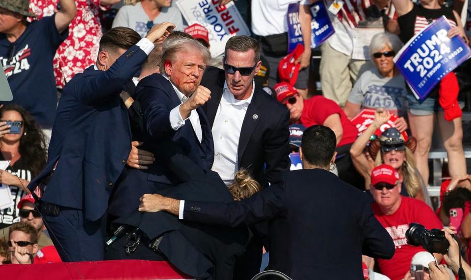 Trump is dragged from the stage, pumping his fist in defiance (Getty)