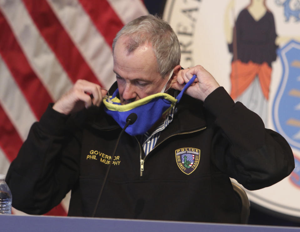 New Jersey Gov. Phil Murphy's removes his mask before giving his daily press briefing at the War Memorial in Trenton, N.J. on Saturday, April 11, 2020. Murphy says he is ordering state transit systems to reduce their capacity by half and will require all transit riders to wear face coverings. (Chris Pedota/The Record via AP, Pool)