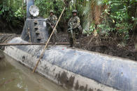 Members of the Colombian Navy stand guard on top of a seized submarine built by drug smugglers in a makeshift shipyard in Timbiqui, department of Cauca February 14, 2011. Colombian authorities said the submersible craft was to be used to transport 8 tons of cocaine illegally into Mexico. REUTERS/Jaime Saldarriaga