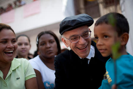 FILE PHOTO: Founder of the National System of Youth and Children's Orchestras of Venezuela Jose Antonio Abreu carries a child as he arrives at a free concert at the low-income neighborhood of La Vega in Caracas August 2, 2009. REUTERS/Carlos Garcia Rawlins/File Photo