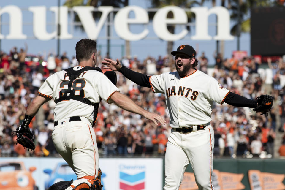 San Francisco Giants closing pitcher Dominic Leone, right, and catcher Buster Posey (28) react after defeating the San Diego Padres in a baseball game in San Francisco, Sunday, Oct. 3, 2021. (AP Photo/John Hefti)