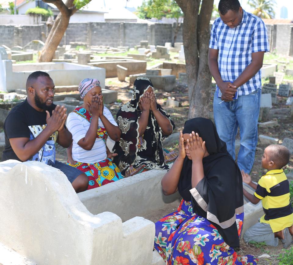 Family members of Rabia Issa and a freelance Tanzanian reporter pray at Issa's grave in Dar es Salaam.