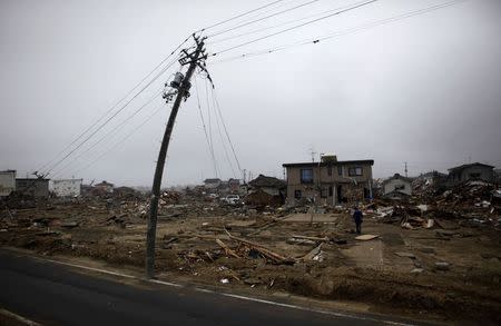 A man walks near a damaged power pole at an area that was devastated by the March 11 earthquake and tsunami, in Watari, Miyagi prefecture, in this April 22, 2011 file photo. REUTERS/Toru Hanai/Files