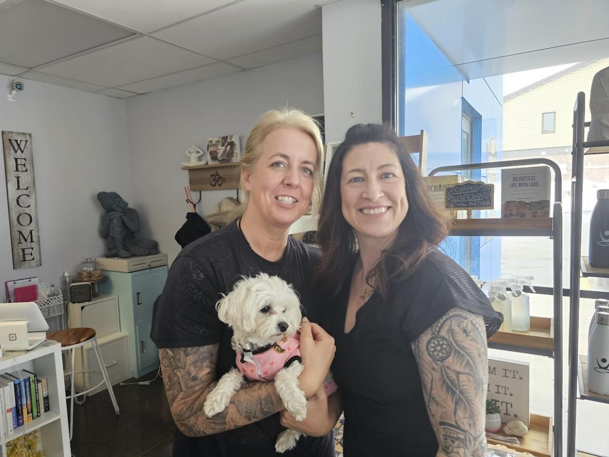 Kelsey Muise, left, and Michelle Lee, holding Lee's dog Lola. Muise is a yoga instructor and offers the class Yoga for Grief in Lee's yoga studio in St. John's Bodhi Hot Yoga.  (Arlette Lazarenko/CBC - image credit)
