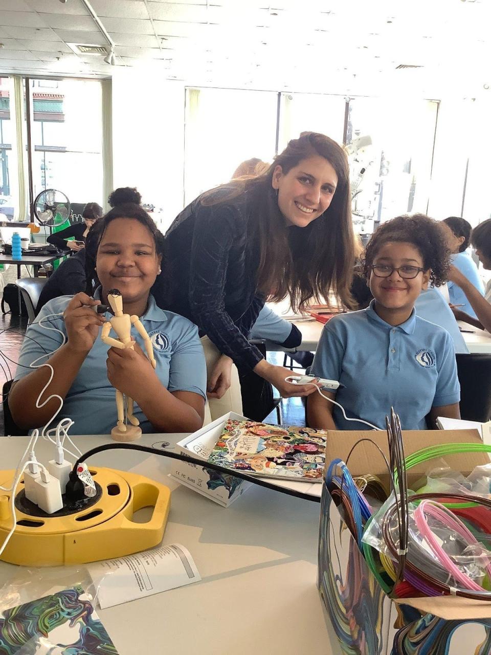 Israeli grad student Lilach Porges, center, works with Our Sisters' School 6th graders Addison P., left, and Nataleyah C., right, at the Swain Studio in downtown New Bedford during an OSS field trip to see Porges' work using robotics to 3D print her fashion designs.