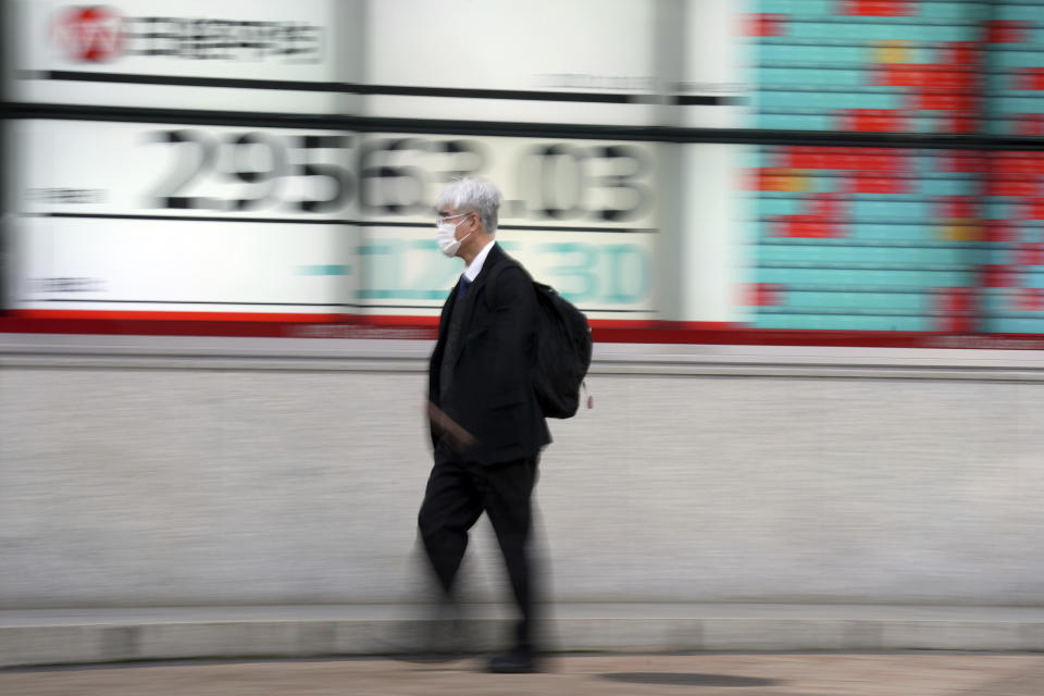 A man wearing a protective mask walks near an electronic stock board showing Japan's Nikkei 225 index at a securities firm Thursday, Nov. 18, 2021, in Tokyo. Asian shares mostly declined Thursday after stock indexes shuffled lower on Wall Street. (AP Photo/Eugene Hoshiko)