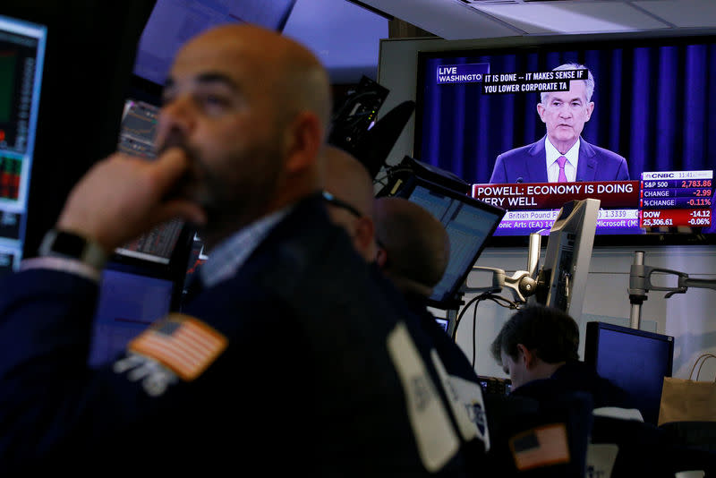 Traders work on the floor of the New York Stock Exchange (NYSE) as a TV screen shows the Fed Rate hike announcment in New York City, U.S. June 13, 2018. REUTERS/Brendan McDermid