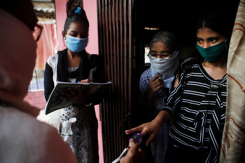 Community health volunteers check the pulse of a resident during a check-up campaign for the coronavirus disease (COVID-19) in Mumbai