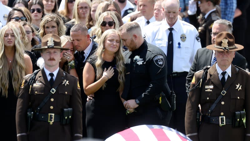 Shayle Terry holds her hand over her heart as she stands behind her father’s casket at Santaquin City Cemetery in Santaquin on Monday, May 13, 2024. Santaquin Police Sgt. Bill Hooser was hit and killed by a semitruck driver on May 5 while assisting a Utah Highway Patrol trooper with a traffic stop.