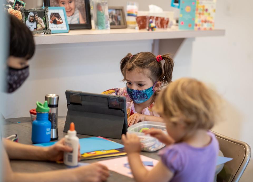 Bach Elementary School first-grader Shahan Eusani (center) of Ann Arbor works on making masks during art class from her home while doing virtual learning on Thursday, April 29, 2021 as her mother Nina Eusani helps her younger sister Anoush Eusani make her own mask.
