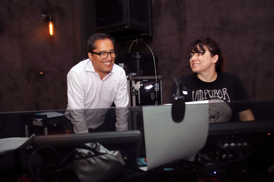 A man and a woman study a control board and smile.