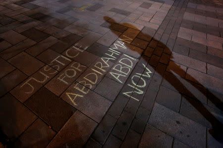 A man casts a shadow near a message written in chalk during a vigil for Abdirahman Abdi, a Somali immigrant to Canada who died after being hospitalized in critical condition following his arrest by Canadian police, in Ottawa, Ontario, Canada, July 26, 2016. REUTERS/Chris Wattie