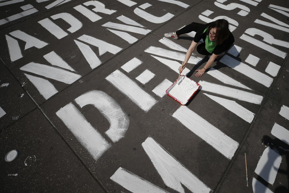 Una mujer ayuda a escribir los nombres de algunas de las más de 3.000 víctimas de feminicidios en la plaza del Zócalo en Ciudad de México, en el Día Internacional de la Mujer, el domingo 8 de marzo de 2020. (AP Foto/Rebecca Blackwell)