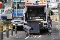 In this Saturday, May 23, 2020 photo, Bangladeshi and Syrian sanitation workers remove garbage from a street, in Beirut, Lebanon. Some 250,000 registered migrant laborers in Lebanon — maids, garbage collectors, farm hands and construction workers — are growing more desperate as a crippling economic and financial crisis sets in, coupled with coronavirus restrictions. With no functioning airports and exorbitant costs of repatriation flights, many are trapped, unable to go home. (AP Photo/Hussein Malla)