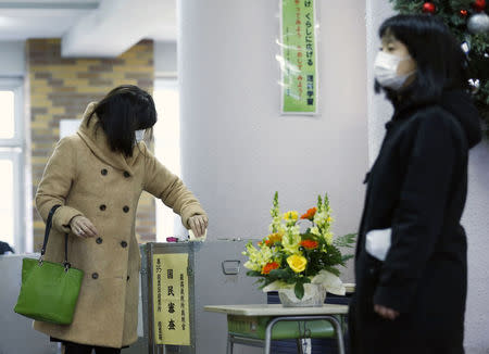 A woman casts her ballot to vote for members of the supreme court as part of Japan's general election in Tokyo, December 14, 2014. REUTERS/Thomas Peter