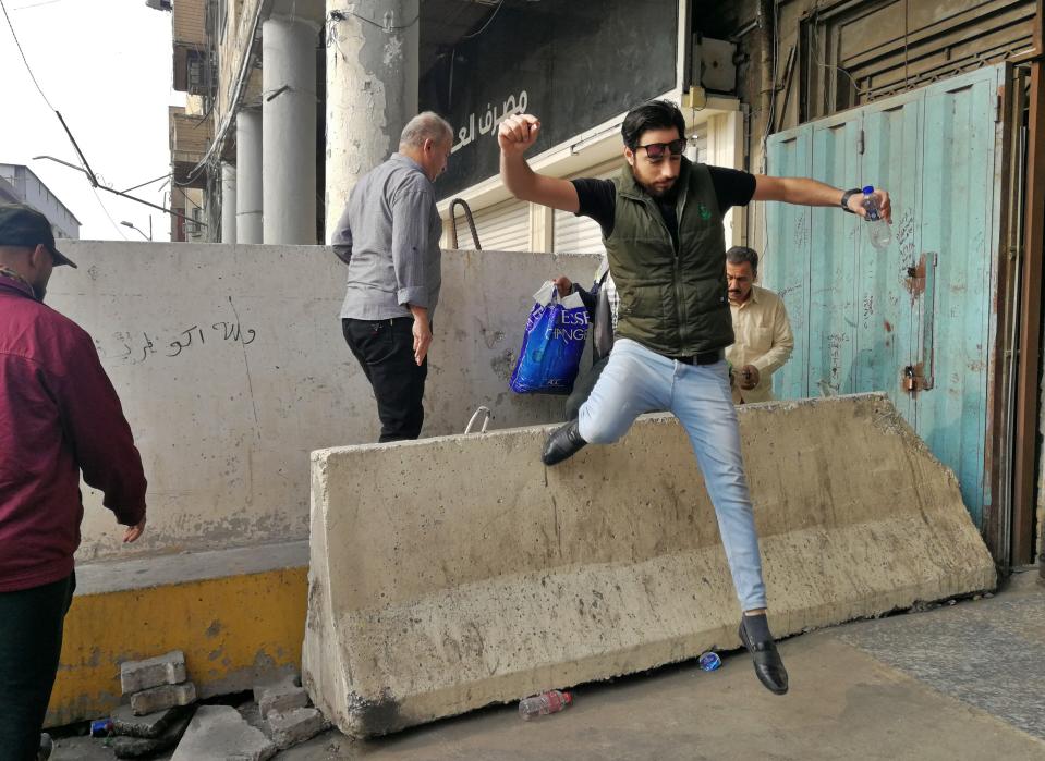 People cross concrete walls set by security forces in Baghdad, Iraq, Monday, Nov. 18, 2019. (AP Photo/Khalid Mohammed)