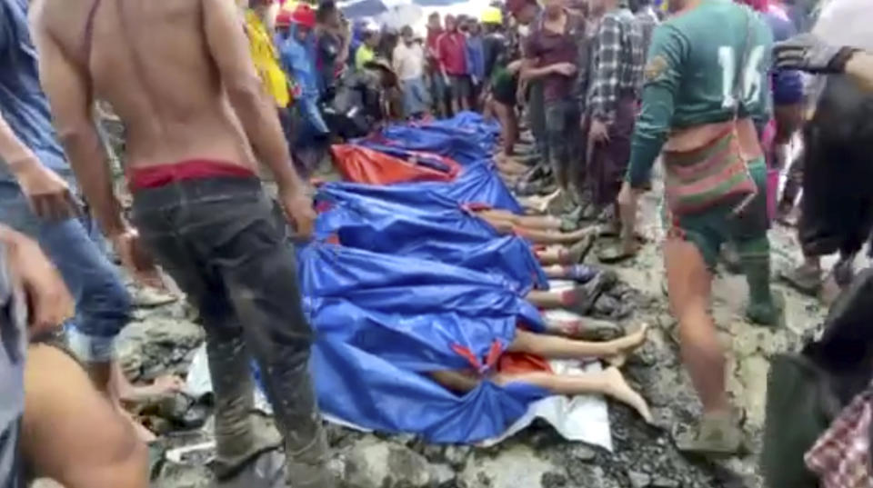 In this image made from video, people gather near the bodies of victims of a landslide near a jade mining area in Hpakant, Kachin state, northern Myanmar Thursday, July 2, 2020. Myanmar government says a landslide at a jade mine has killed dozens of people. (AP Photo/Zaw Moe Htet)