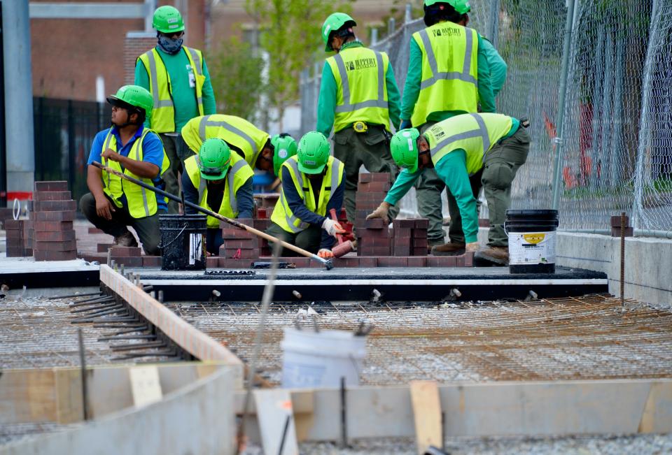 Workers laying brick along a walkway at Meritus Park on Tuesday, four days before the park's soft opening for the Flying Boxcars' opening home stand.