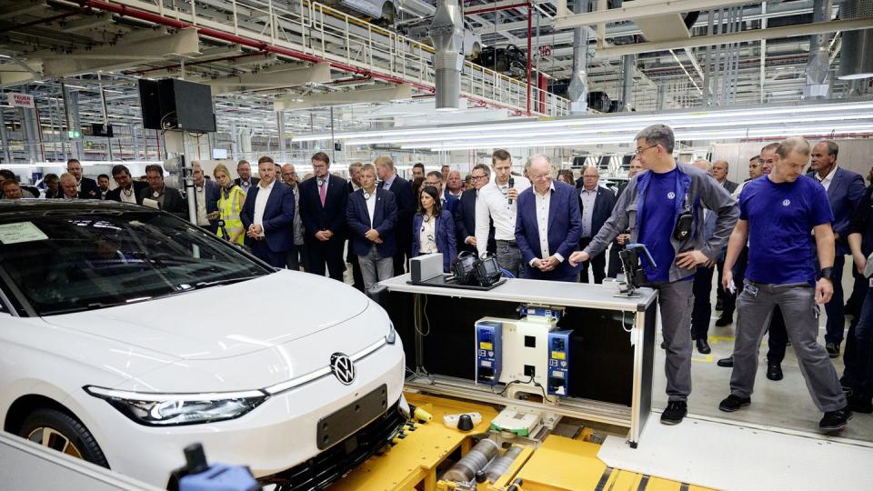 volkswagen id7 sedan sits at the end of the assembly line with workers standing around it