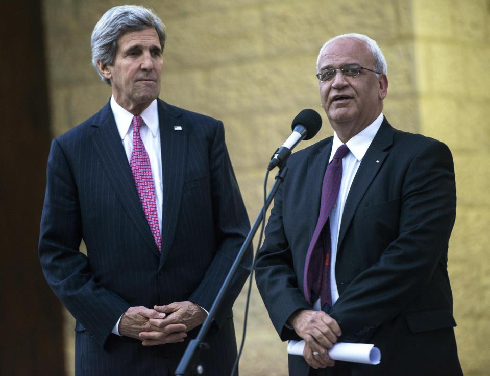 FILE - In this Jan. 4, 2014 file photo, U.S. Secretary of State John Kerry, left, listens to Palestinian negotiator Saeb Erekat make a statement to the press after meeting with Palestinian President Mahmoud Abbas at the presidential compound in the West Bank city of Ramallah. Erekat, a veteran peace negotiator and prominent international spokesman for the Palestinians for more than three decades, died Tuesday, Nov. 10, 2020. He was 65. (AP Photo/Brendan Smialowski, Pool, File)