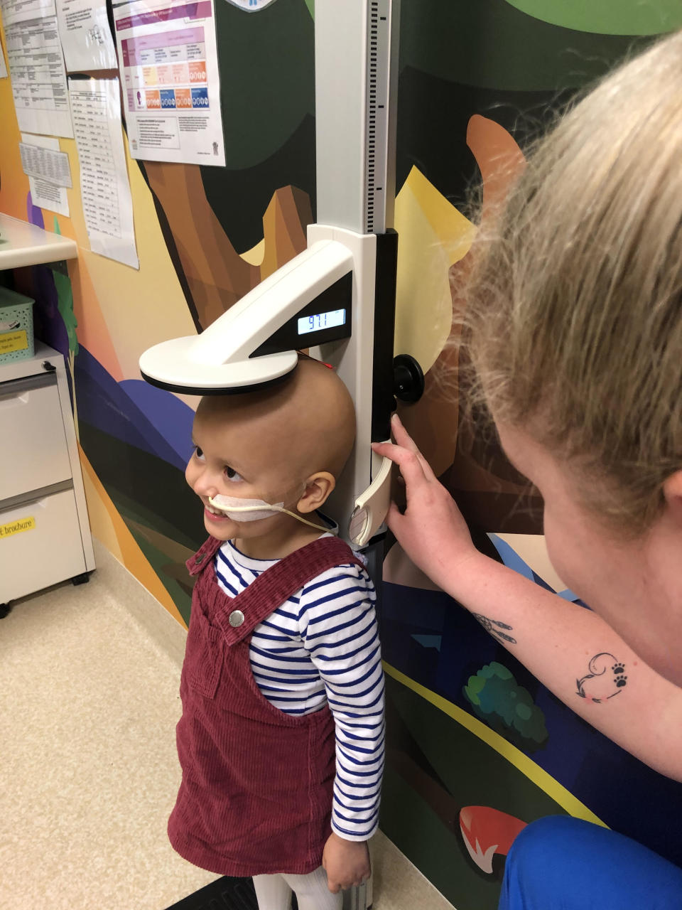 Scout Pederson smiling as nurses measure her height while in hospital. 