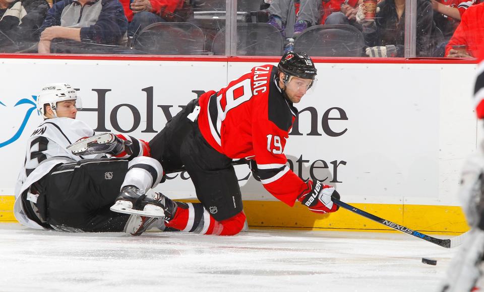 NEWARK, NJ - FEBRUARY 14:  Travis Zajac #19 of the New Jersey Devils plays the puck against Dustin Brown #23 of the Los Angeles Kings at the Prudential Center on February 14, 2016 in Newark, New Jersey.  (Photo by Jim McIsaac/Getty Images)