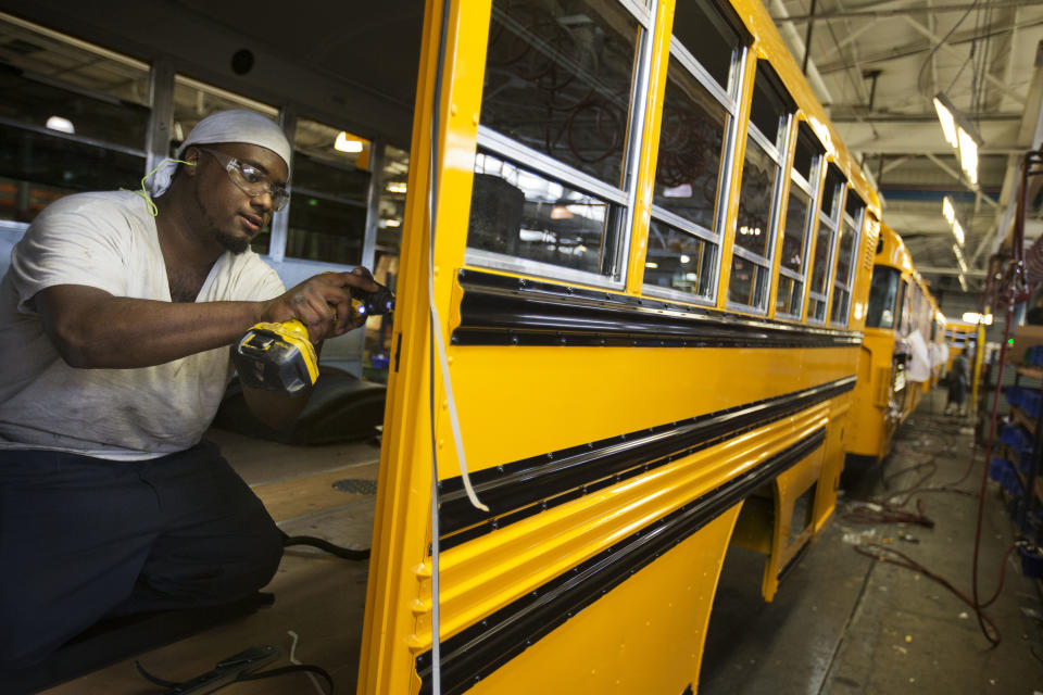 FOR USE AS DESIRED - In this Sept. 18, 2015 photo an employee works on a school bus on the assembly line at Blue Bird Corporation's manufacturing facility in Fort Valley, Ga. Blue Bird Corporation, one of the nation's leading manufacturer of school buses, employees about 1600 workers and has sold more than 550,000 buses since its formation in 1927. (AP Photo/David Goldman)
