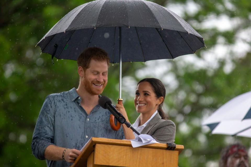 <p>Meghan Markle lets Prince Harry stand under her umbrella as he carries on with a speech after it started to rain in Dubbo, Australia. </p>