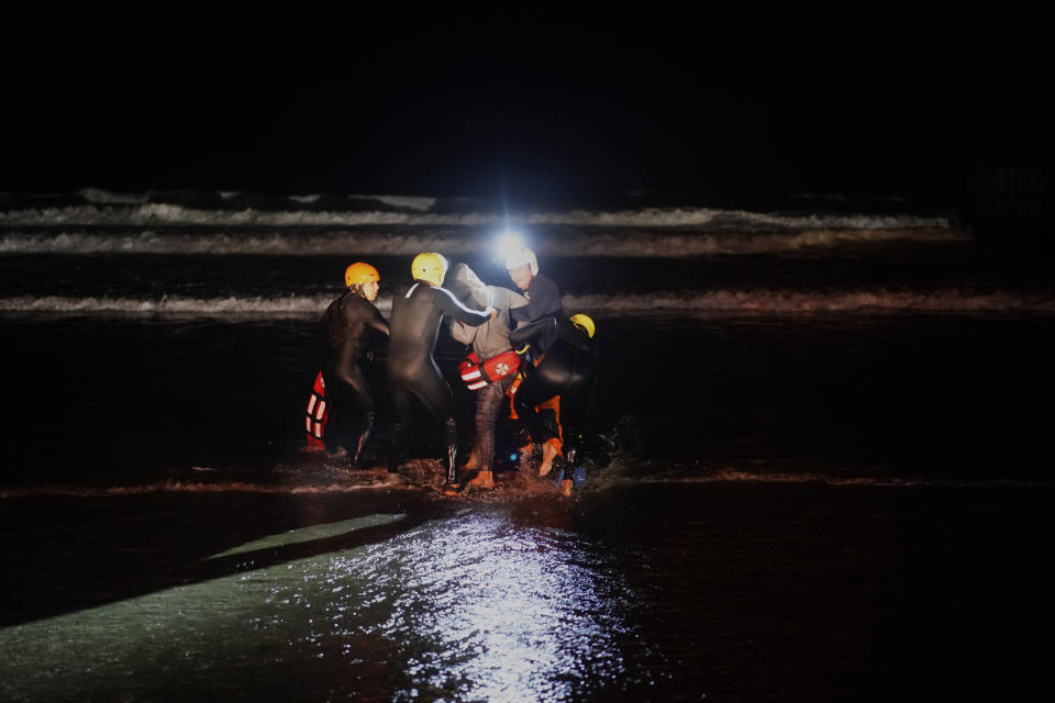 Rescuers hold a Honduran migrant who tried to cross the U.S. border by the sea in Tijuana beach, Mexico, Thursday, Nov. 29, 2018. Aid workers and humanitarian organizations expressed concerns Thursday about the unsanitary conditions at the sports complex in Tijuana where more than 6,000 Central American migrants are packed into a space adequate for half that many people and where lice infestations and respiratory infections are rampant. (AP Photo/Ramon Espinosa)