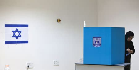 An Israeli Arab woman stands behind a booth as she casts her ballot for the parliamentary election at a polling station in the town of Tira, in this January 22, 2013 file photo. REUTERS/Nir Elias/Files