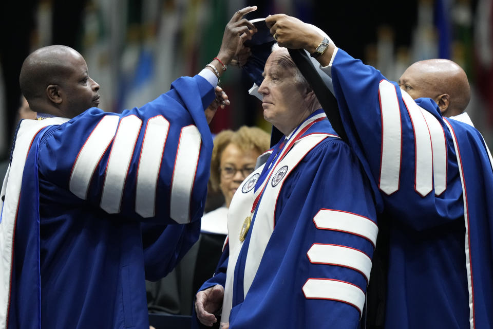 Howard University President Wayne A. I. Frederick, left, and Laurence Morse, Chairman, Howard University Board of Trustees, right, present President Joe Biden with an honorary degree at Howard University's commencement in Washington, Saturday, May 13, 2023. (AP Photo/Alex Brandon)