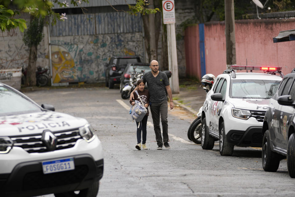 A student leaves the Thomazia Montoro school with her father after a fatal stabbing at the school in Sao Paulo, Brazil, Monday, March 27, 2023. A 13-year-old student fatally stabbed a 71-year-old teacher and wounded three teachers and two fellow students Monday in a knife attack at the public school, state officials said. (AP Photo/Andre Penner)