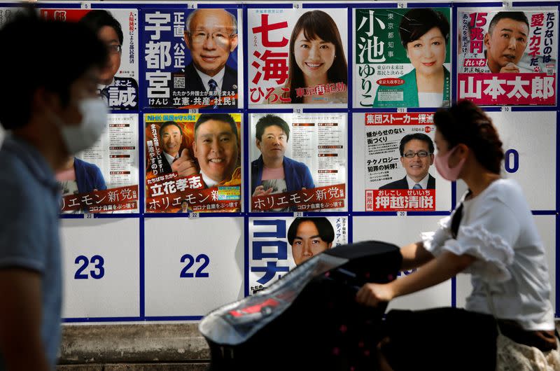 Passersby wearing protective face masks walk past candidate posters, including current governor Yuriko Koike, for the upcoming Tokyo governor election during the spread of the coronavirus disease (COVID-19), in Tokyo