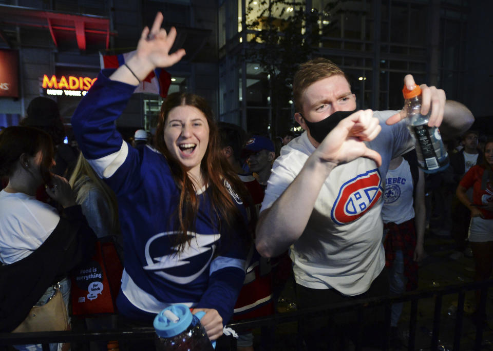 A Tampa Bay Lightning fan and a Montreal Canadiens fan react as they watch coverage of the end of Game 5 of the NHL hockey Stanley Cup Finals, outside the Bell Centre in Montreal on Wednesday, July 7, 2021. (Ryan Remiorz/The Canadian Press via AP)