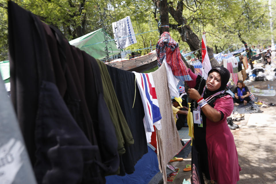 An anti-government protester hangs her clothes to dry at a camp site in downtown Bangkok, Thailand, Sunday, May 11, 2014. Thai anti-government protesters who have been camped out in several location in Bangkok packed their tents as they ramped up their efforts to bring down what remains of Prime Minister Yingluck Shinawatra's administration by laying siege to television stations, surrounding state offices and demanding lawmakers help them install a non-elected prime minister to rule the country. (AP Photo/Vincent Thian)