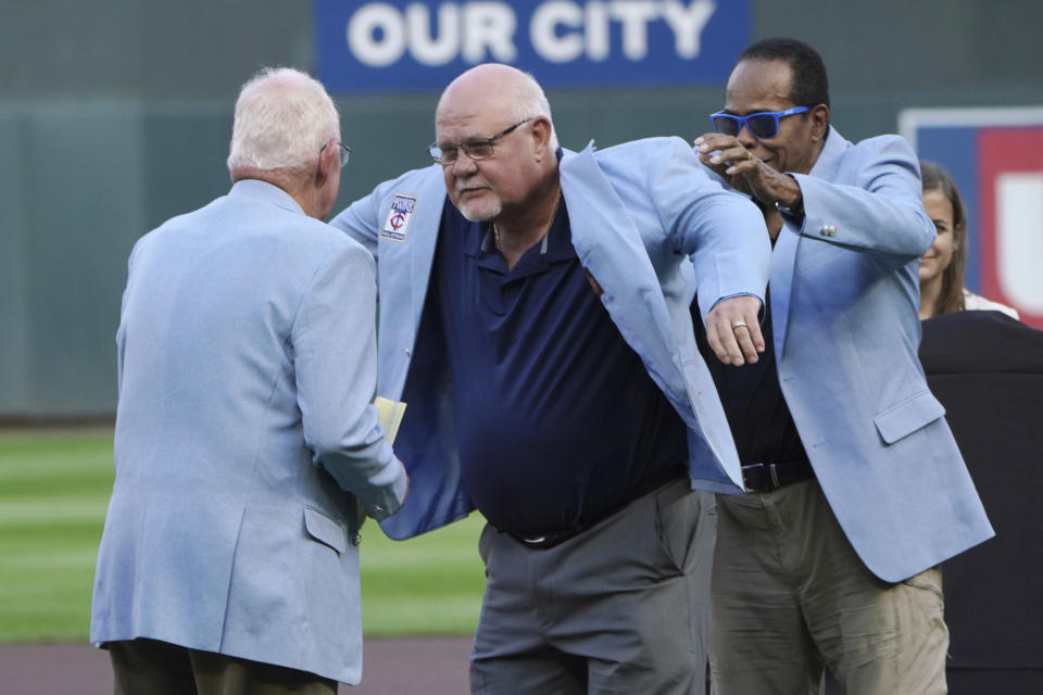 Former Minnesota Twins manger Ron Gardenhire, center, receives a coat from his predecessor, former manager Tom Kelly, as Twins great Rod Carew. Right, helps putting it on Gardenhire after he was inducted into the Twins Hall of Fame prior to the Twins' baseball game against the Texas Rangers, Saturday, Aug, 20, 2022, in Minneapolis. (AP Photo/Jim Mone0