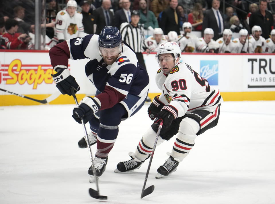 Colorado Avalanche defenseman Kurtis MacDermid, left, clears the puck as Chicago Blackhawks center Tyler Johnson defends in the second period of an NHL hockey game Monday, March 20, 2023, in Denver. (AP Photo/David Zalubowski)