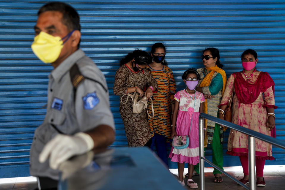 A security guard and visitors wear masks as a precaution against COVID-19 at the entrance to the zoo in Kolkata, India, Sunday, March 15, 2020. For most people, the new coronavirus causes only mild or moderate symptoms. For some, it can cause more severe illness, especially in older adults and people with existing health problems. (AP Photo/Bikas Das)