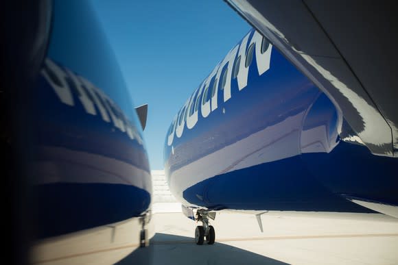 Blue airplane with Southwest logo reflected in side of building on tarmac.