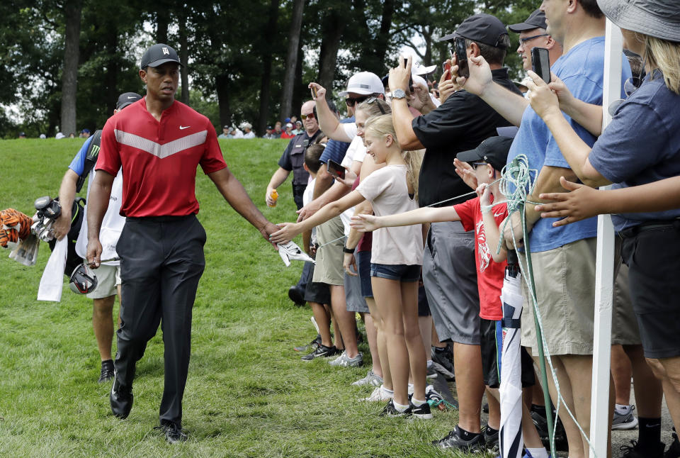 Tiger Woods, left, greets fans as he walks to the 14th fairway after hitting his tee shot during the final round of the BMW Championship golf tournament at Medinah Country Club, Sunday, Aug. 18, 2019, in Medinah, Ill. (AP Photo/Nam Y. Huh)