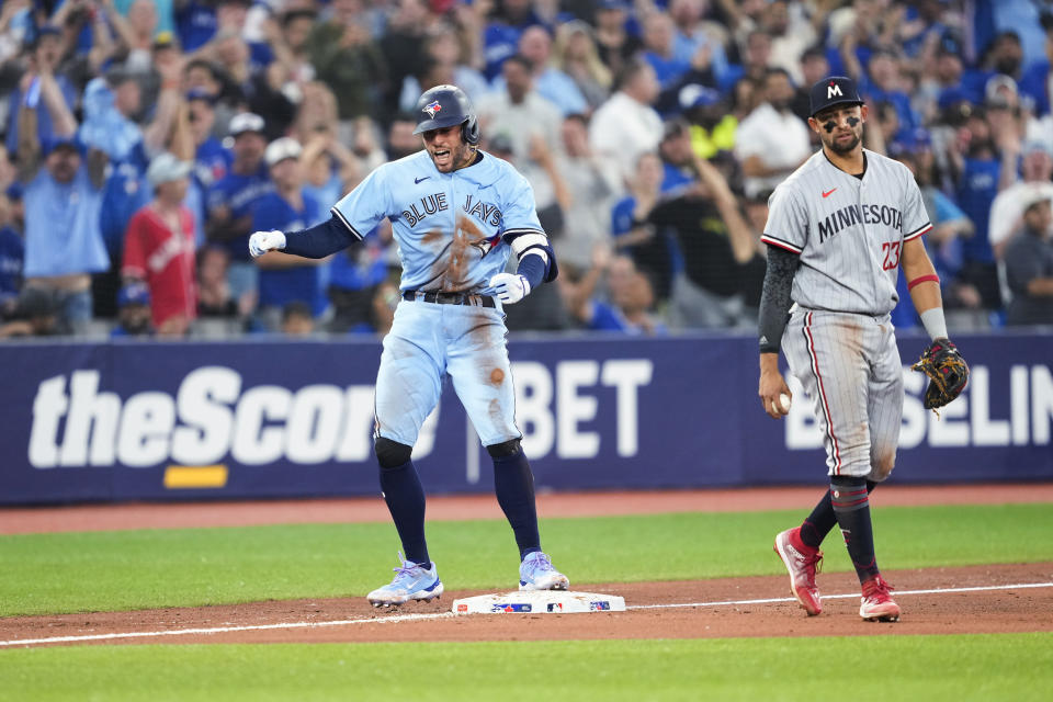 Toronto Blue Jays' George Springer (4) celebrates beside Minnesota Twins third baseman Royce Lewis after hitting an RBI double and advancing to third during the sixth inning of a baseball game Friday, June 9, 2023, in Toronto. (Mark Blinch/The Canadian Press via AP)