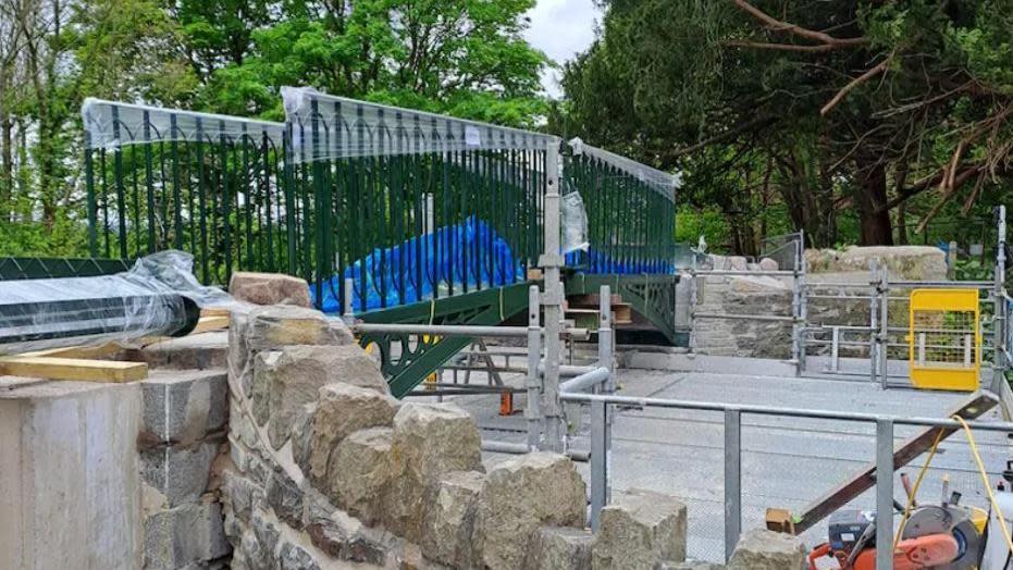 The footbridge newly installed, with visible works still being conducted around it and scaffolding in place